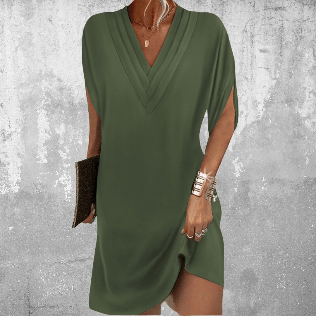 Green dress worn by a person against a textured gray background